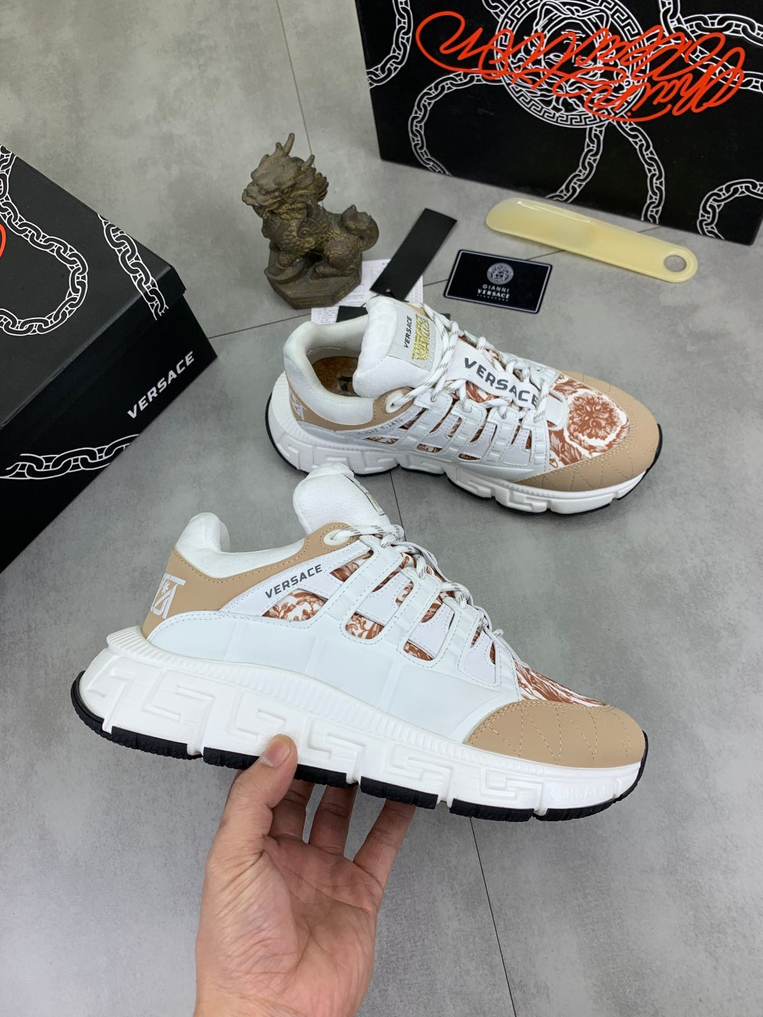 White and tan low-top sneakers with brown floral toe detail, pair view