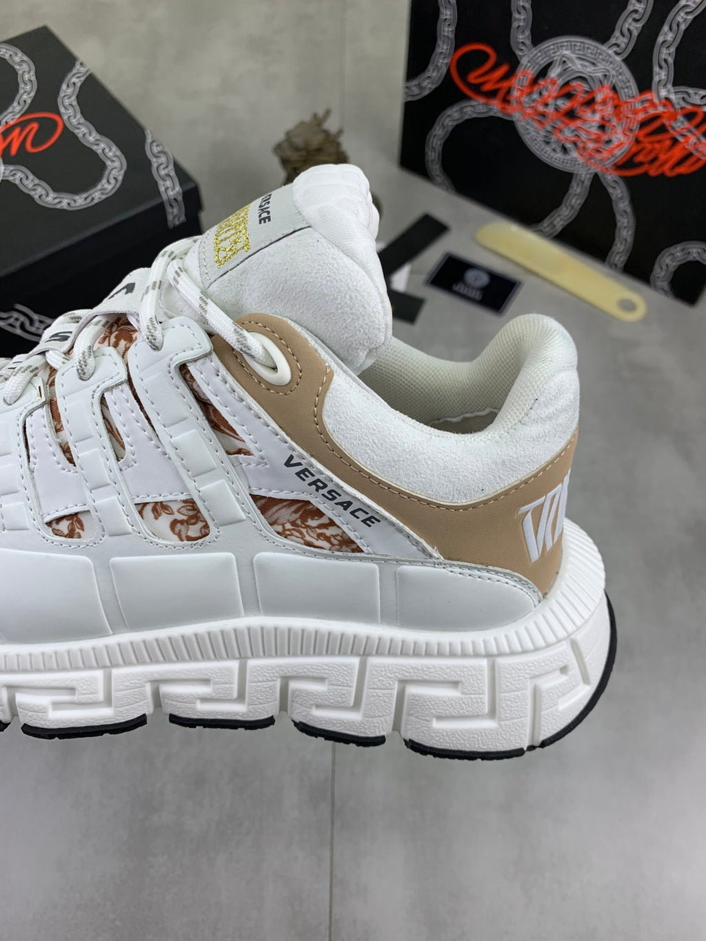 White low-top sneakers with tan side panel and thick tread sole detail