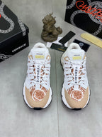 Pair of white low-top sneakers with tan panels and brown floral toe accents