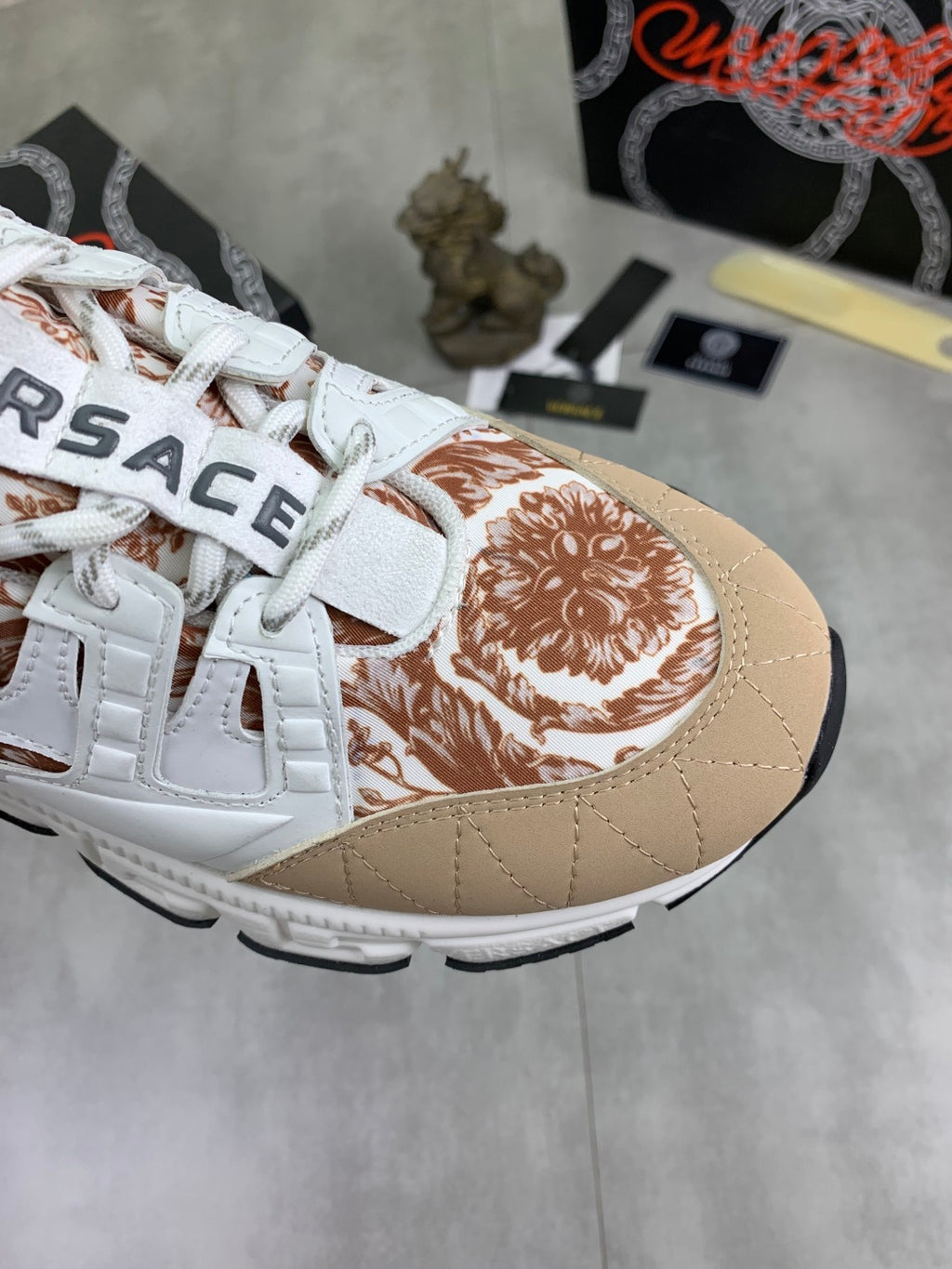 Close-up of white low-top sneaker toe with tan background and brown floral print