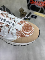 Close-up of white low-top sneaker toe with tan background and brown floral print