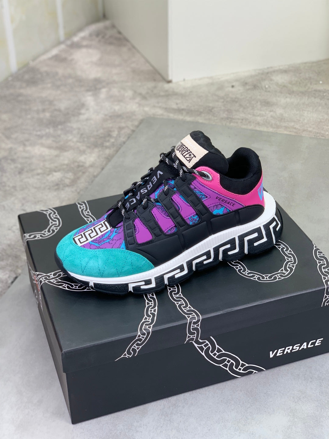 Versace sneakers on box, black and turquoise with purple panels, neon pink stripe accents