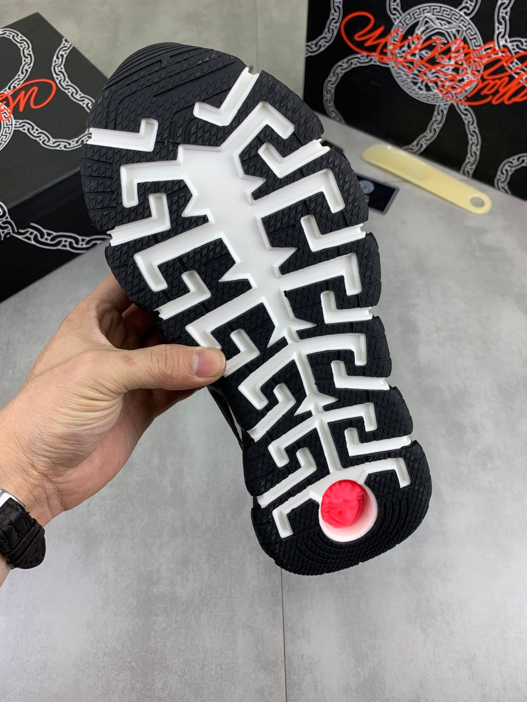 Versace sneakers outsole, black tread with white geometric pattern and red circular detail