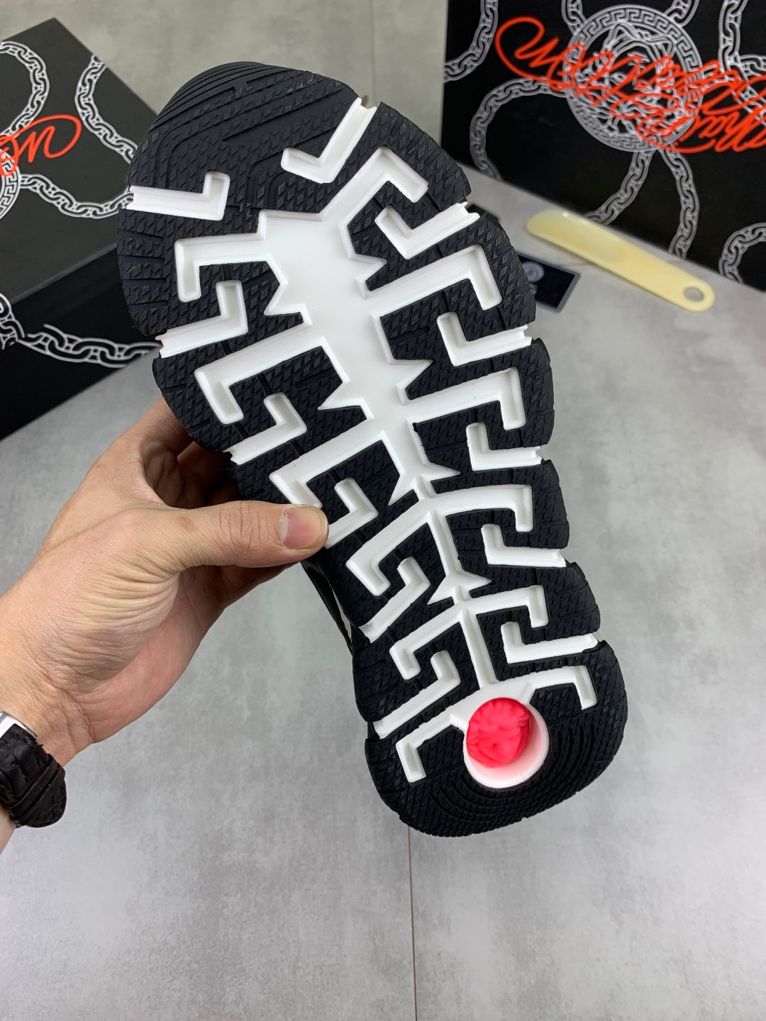 Versace sneakers outsole, black tread with white geometric pattern and red circular detail