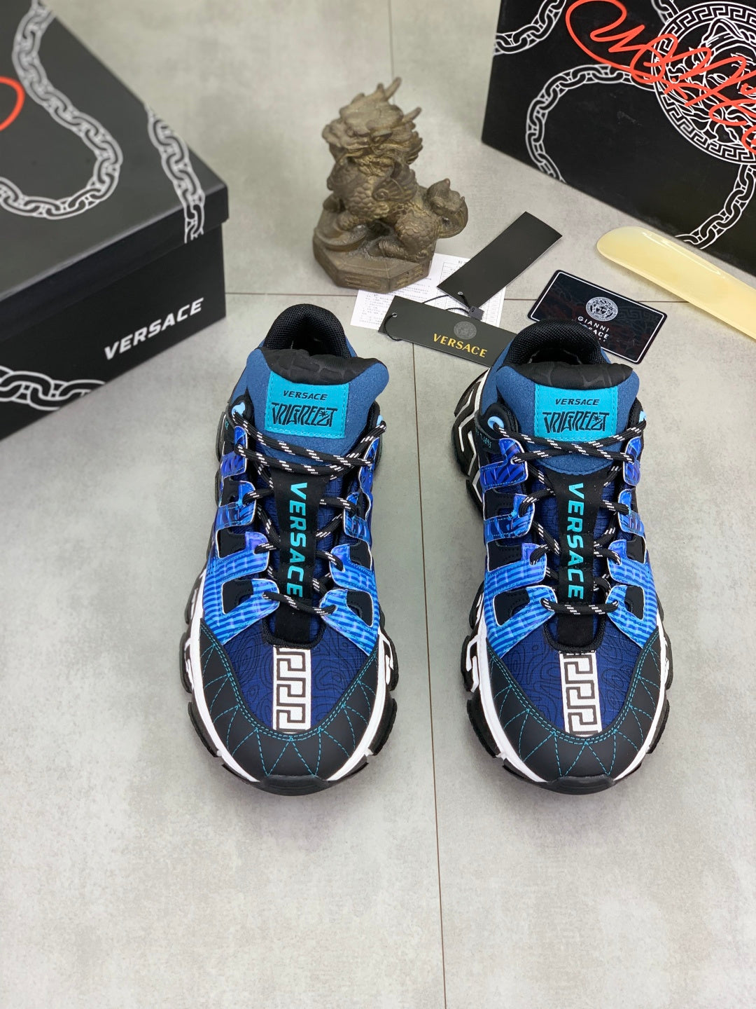Pair of blue and black Versace sneakers with Velcro straps and white Greek key panels