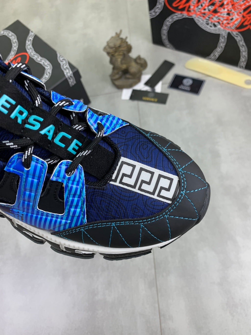 Blue and black Versace sneakers close-up, featuring Velcro tabs and Greek key side print