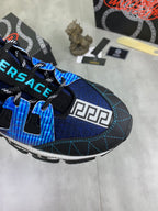 Blue and black Versace sneakers close-up, featuring Velcro tabs and Greek key side print