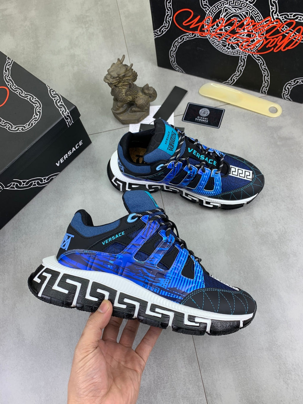 Blue and black Versace sneakers with white sole, shown from front and side