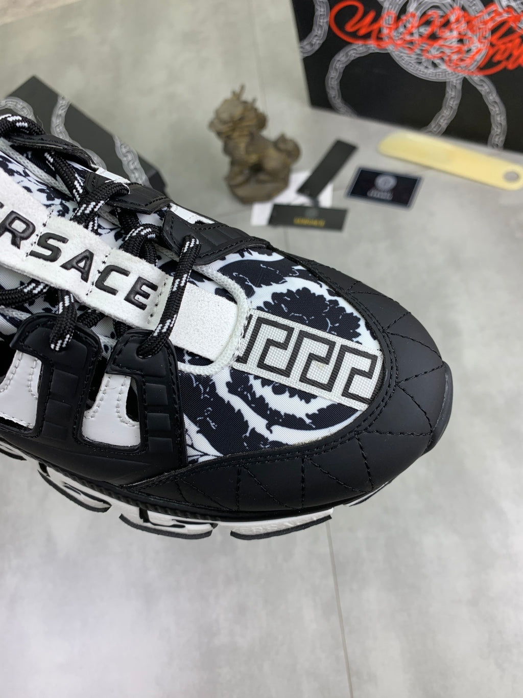 Close-up of black and white sneakers with patterned quarter panel, straps, and logo
