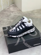 Black sneaker with white laces, white Greca-style trim, and logo patch on side