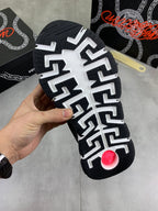 Black sneaker outsole with raised white pattern and small red accent on tread