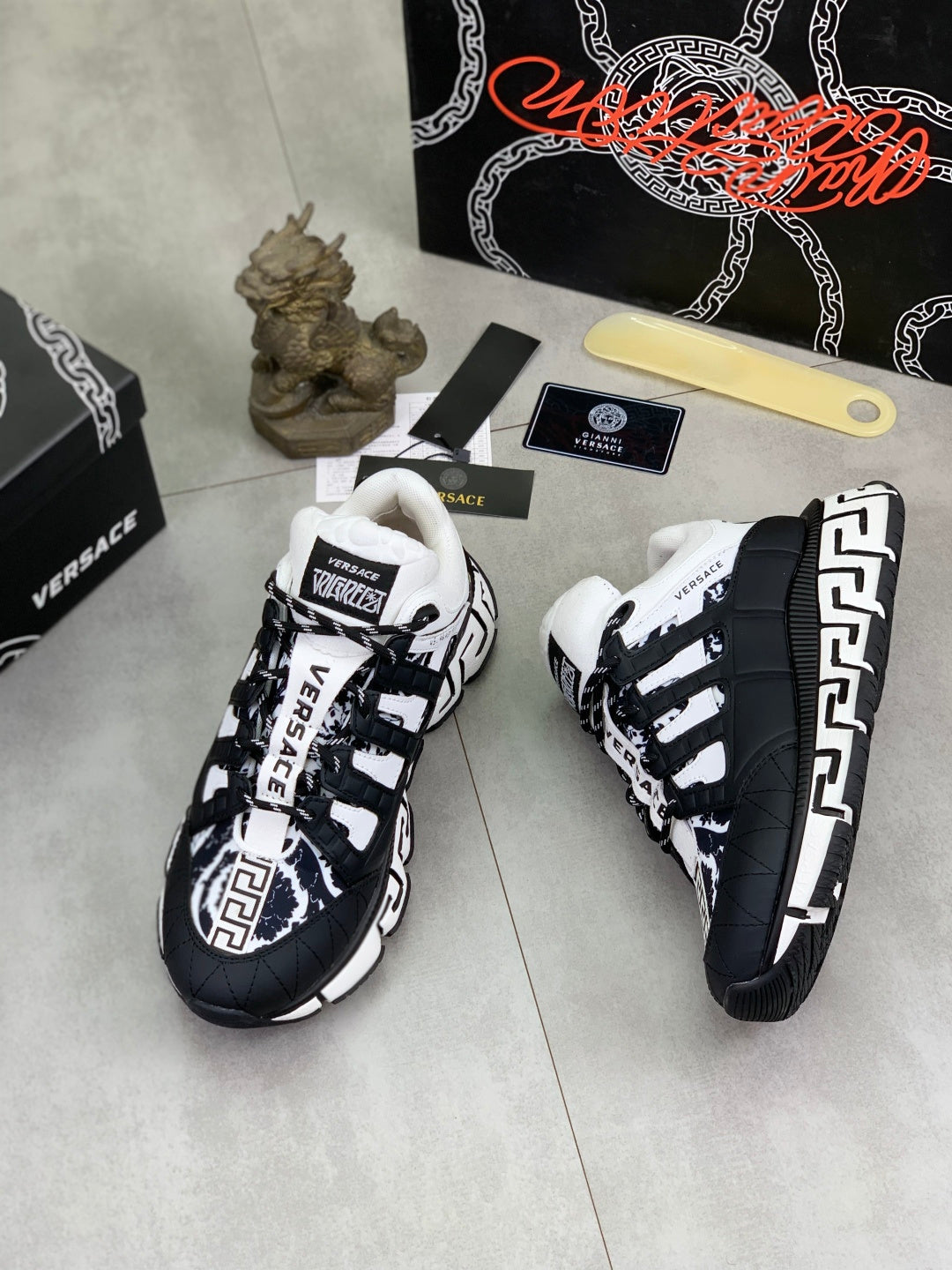 Black and white sneakers with white laces and Greca-style side trim, front view