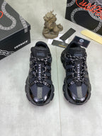 Pair of Versace luxury sneakers, black with blue accents, lace-up and chunky sole