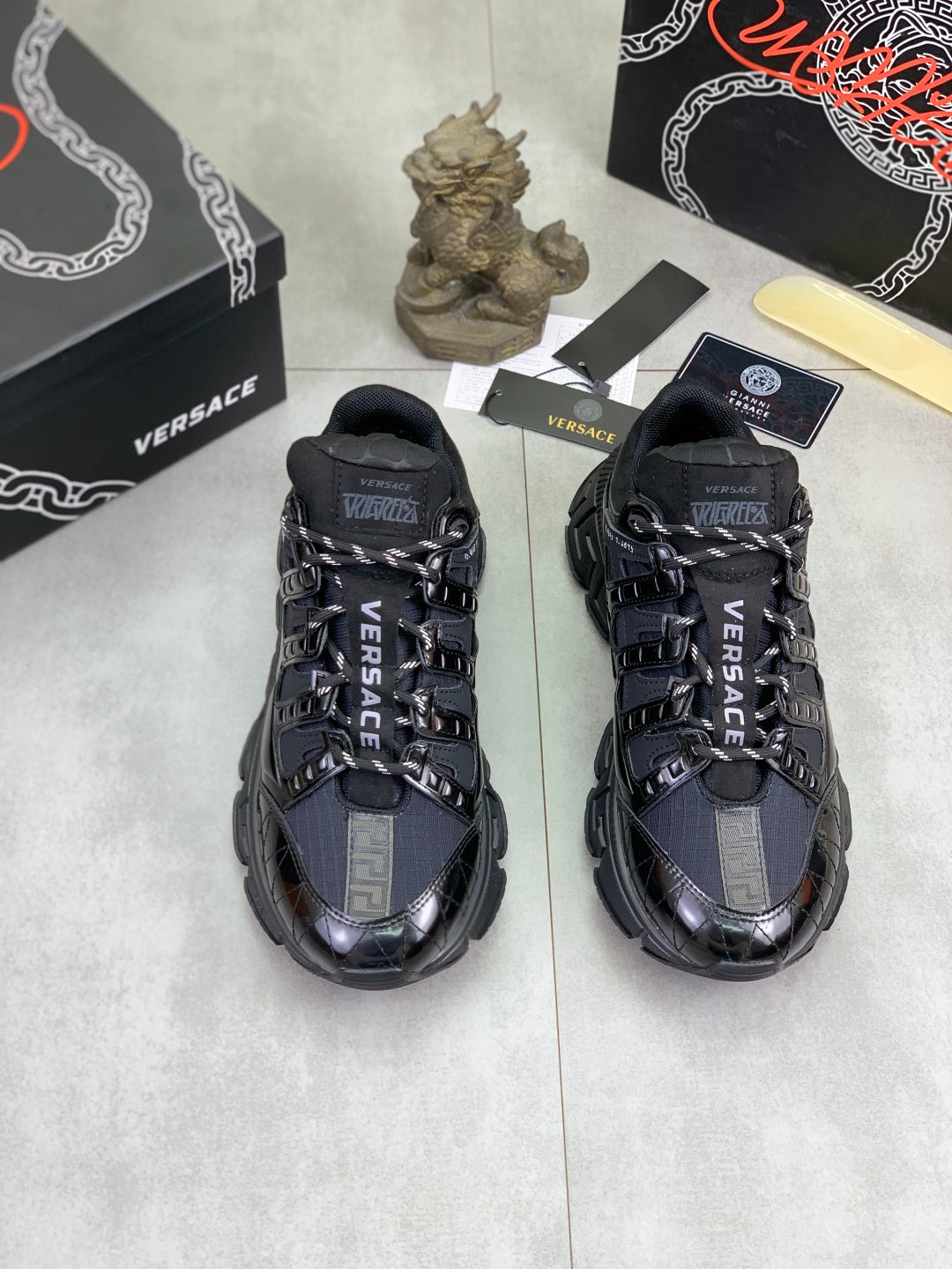Pair of Versace luxury sneakers, black with blue accents, lace-up and chunky sole