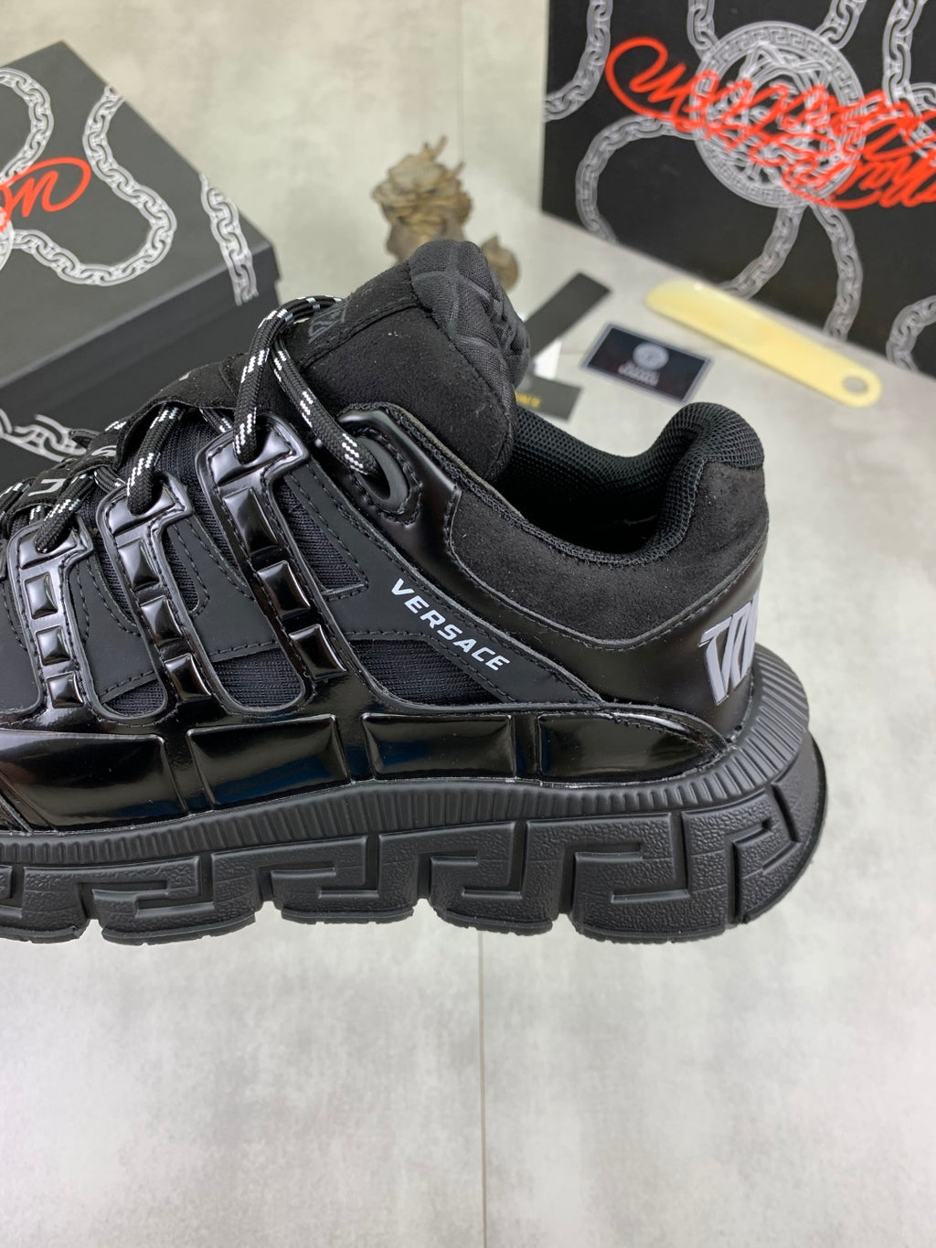 Versace luxury sneaker side, black with VERSACE logo and chunky ribbed sole
