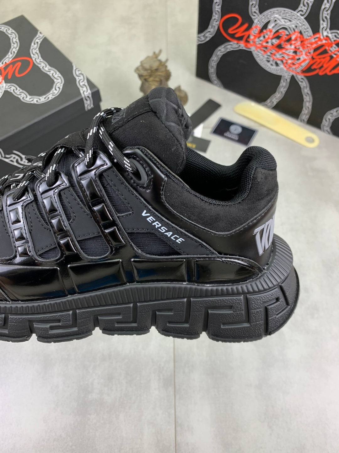 Versace luxury sneaker side, black with VERSACE logo and chunky ribbed sole