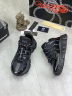 Versace luxury sneakers, side view with textured tread sole and black strap panels