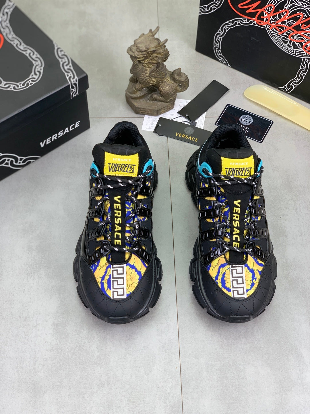 Pair of sneakers, black uppers with blue and yellow graphic panels and logo straps