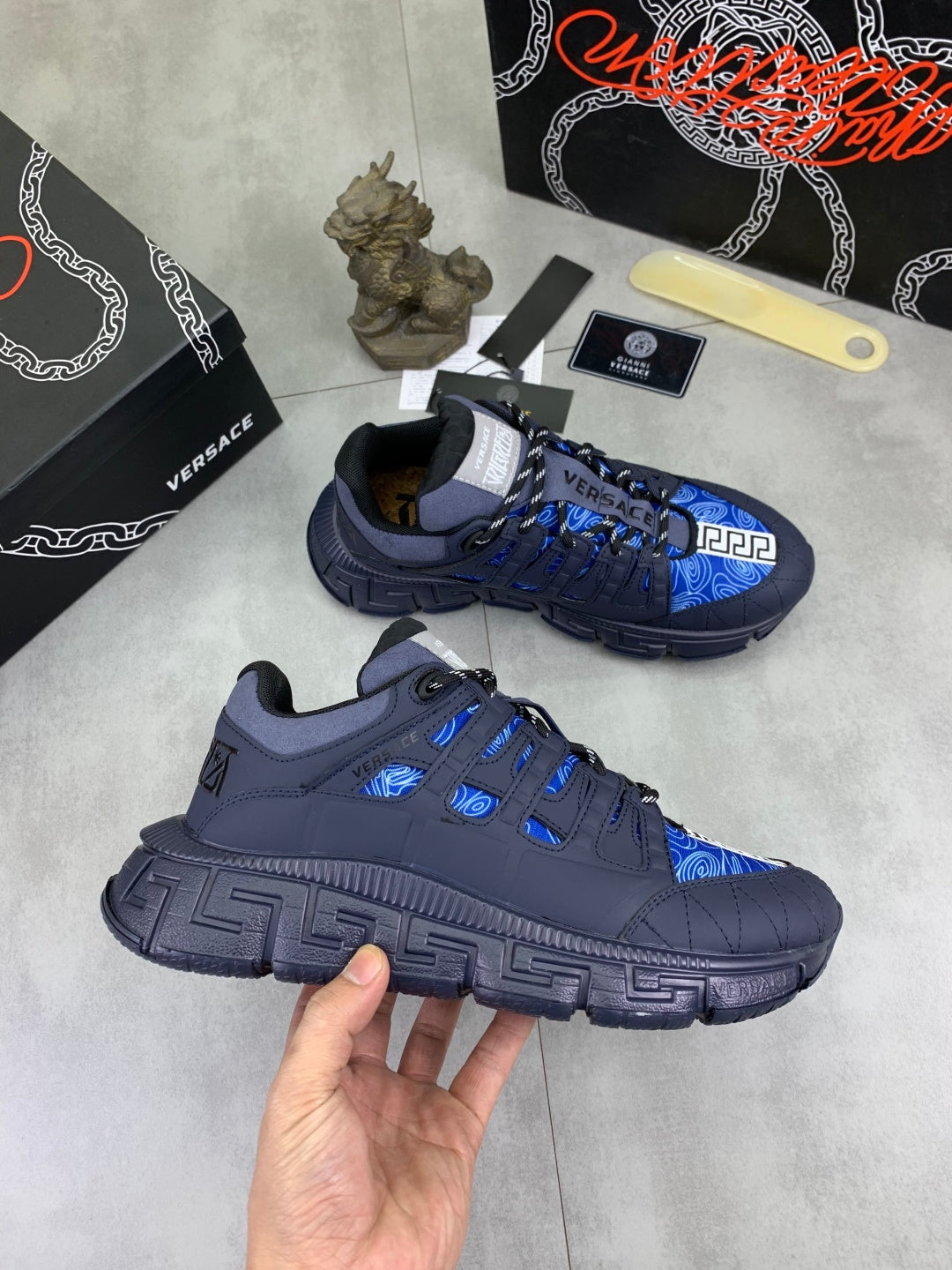 Versace luxury sneakers on display, dark navy and blue laced uppers with logo patch