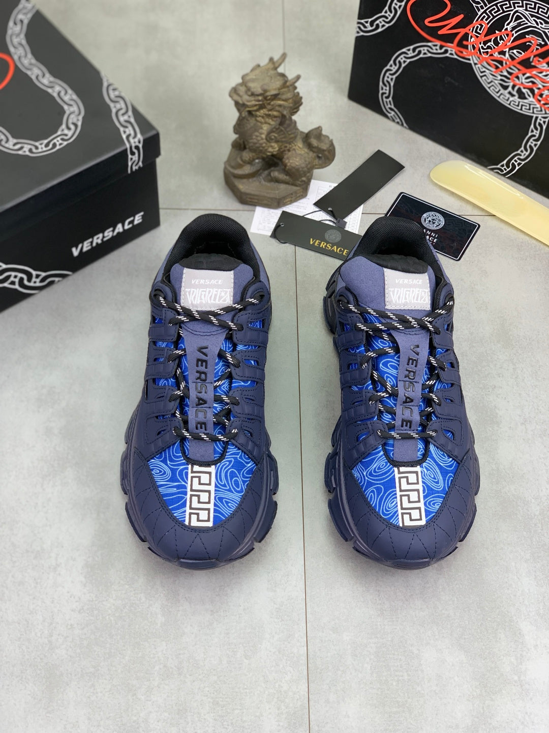 Versace luxury sneakers pair, dark navy upper with bright blue accents and laces