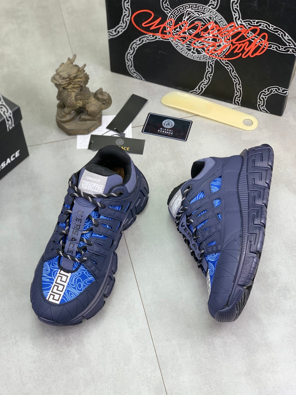 Versace luxury sneakers side view, dark navy with blue geometric panel accents
