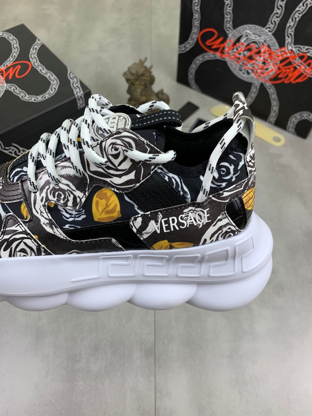 Front view of printed sneakers with white laces, black-and-white rose graphic and gold-yellow accents.