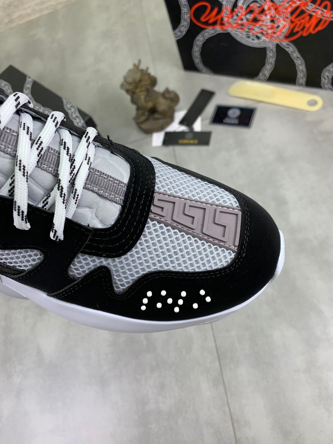 Versace sneakers side view, black and gray mesh upper with white laces and stud accents
