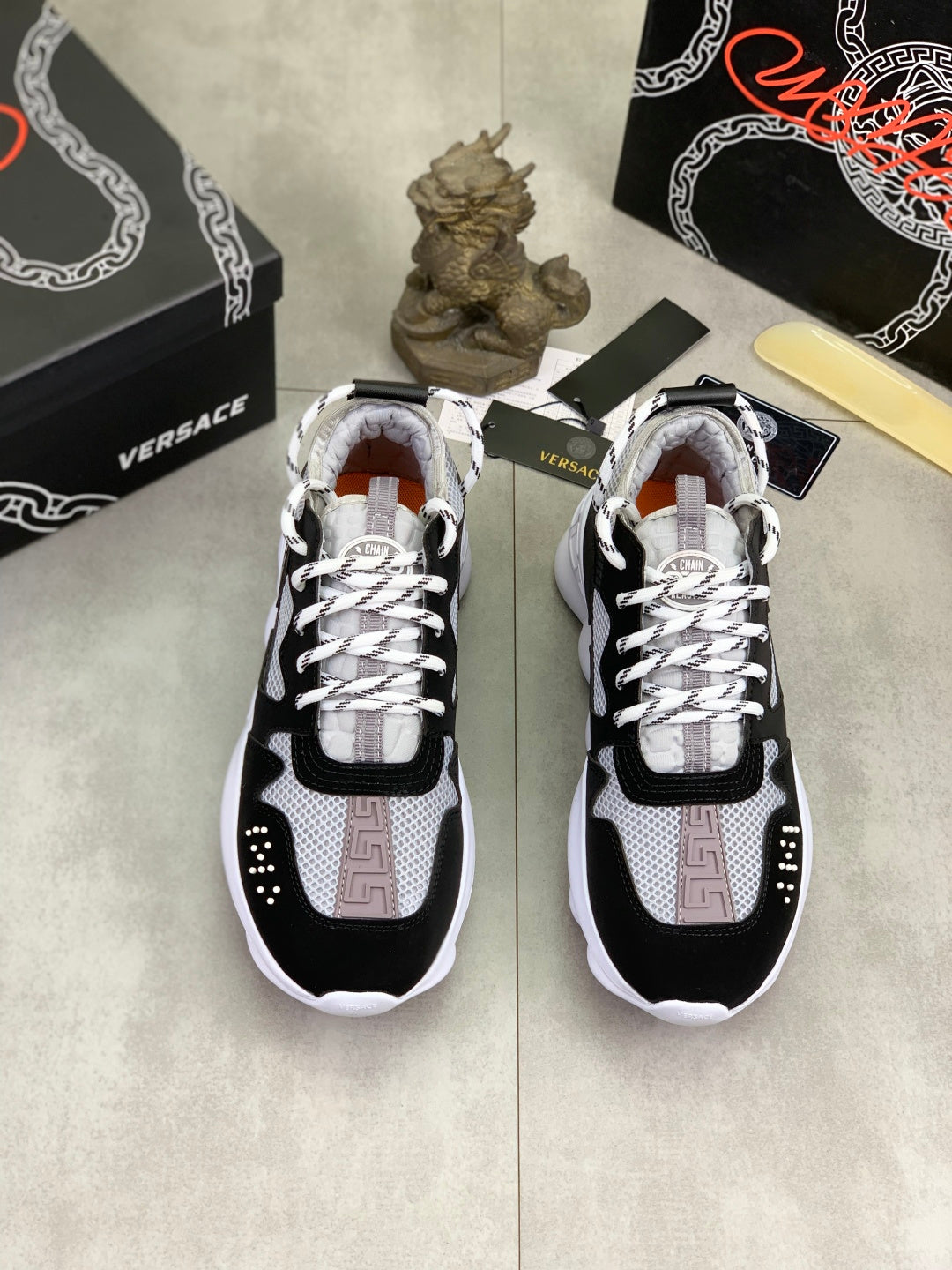 Pair of black and white Versace lace-up sneakers with patterned tongue accents