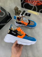 Versace chunky sneakers held in hand, blue orange black uppers with white sole