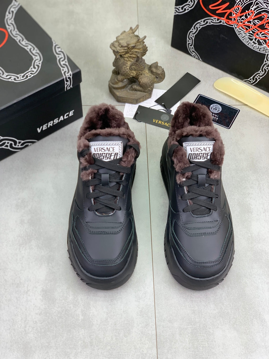 Pair of Luxury Versace dark gray sneakers with taupe faux-fur collar and lace-up tops.