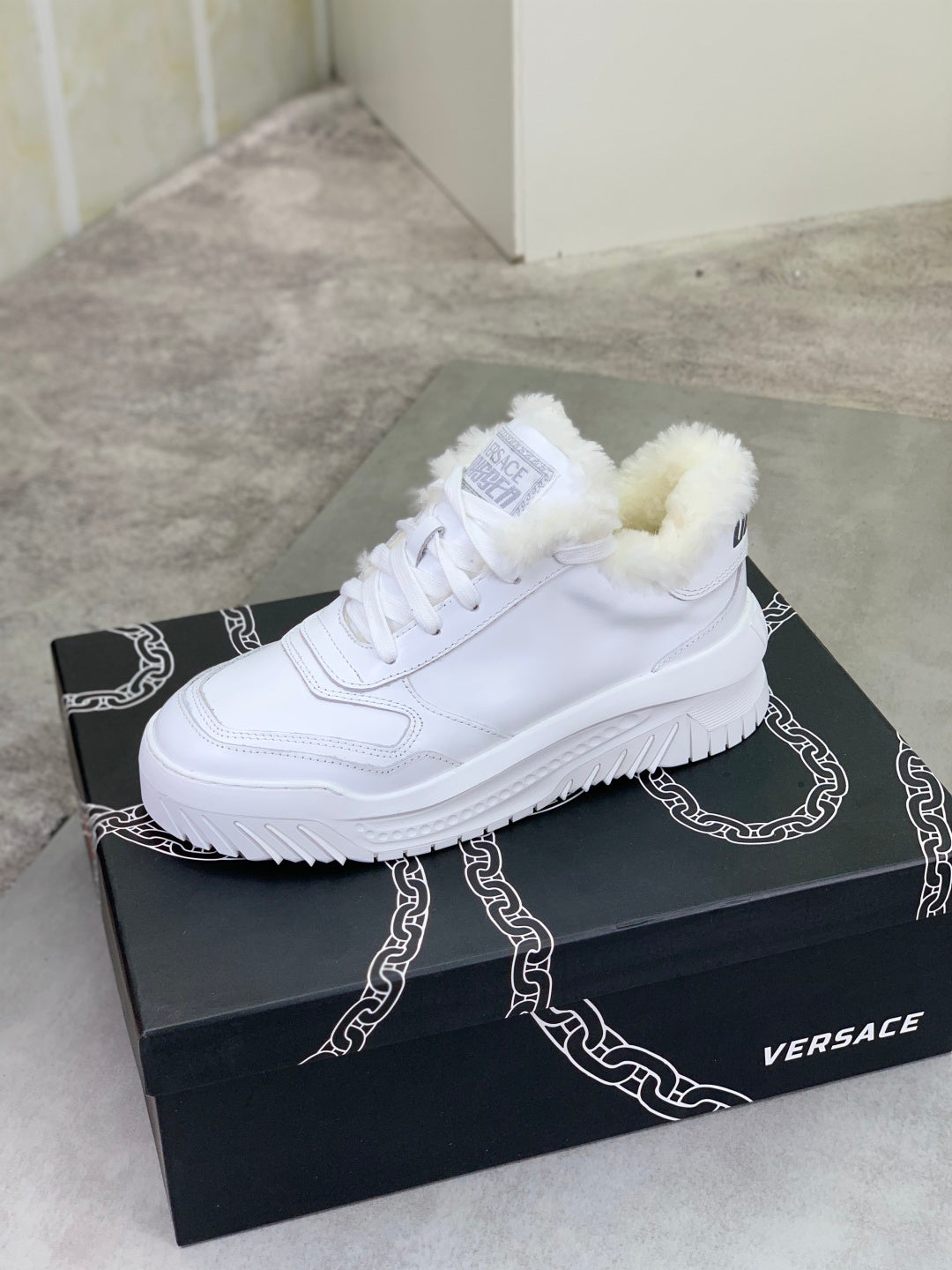 Versace white lace-up sneaker with fuzzy collar on a black box