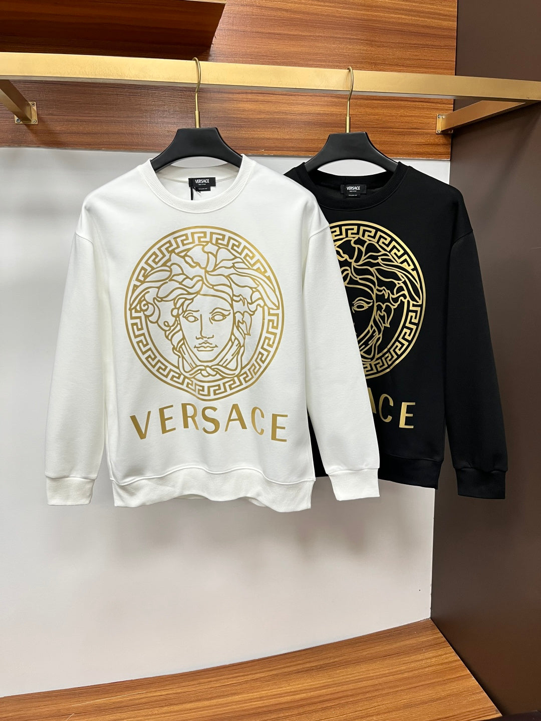 White and black crewneck sweatshirts with gold Medusa emblem and VERSACE lettering