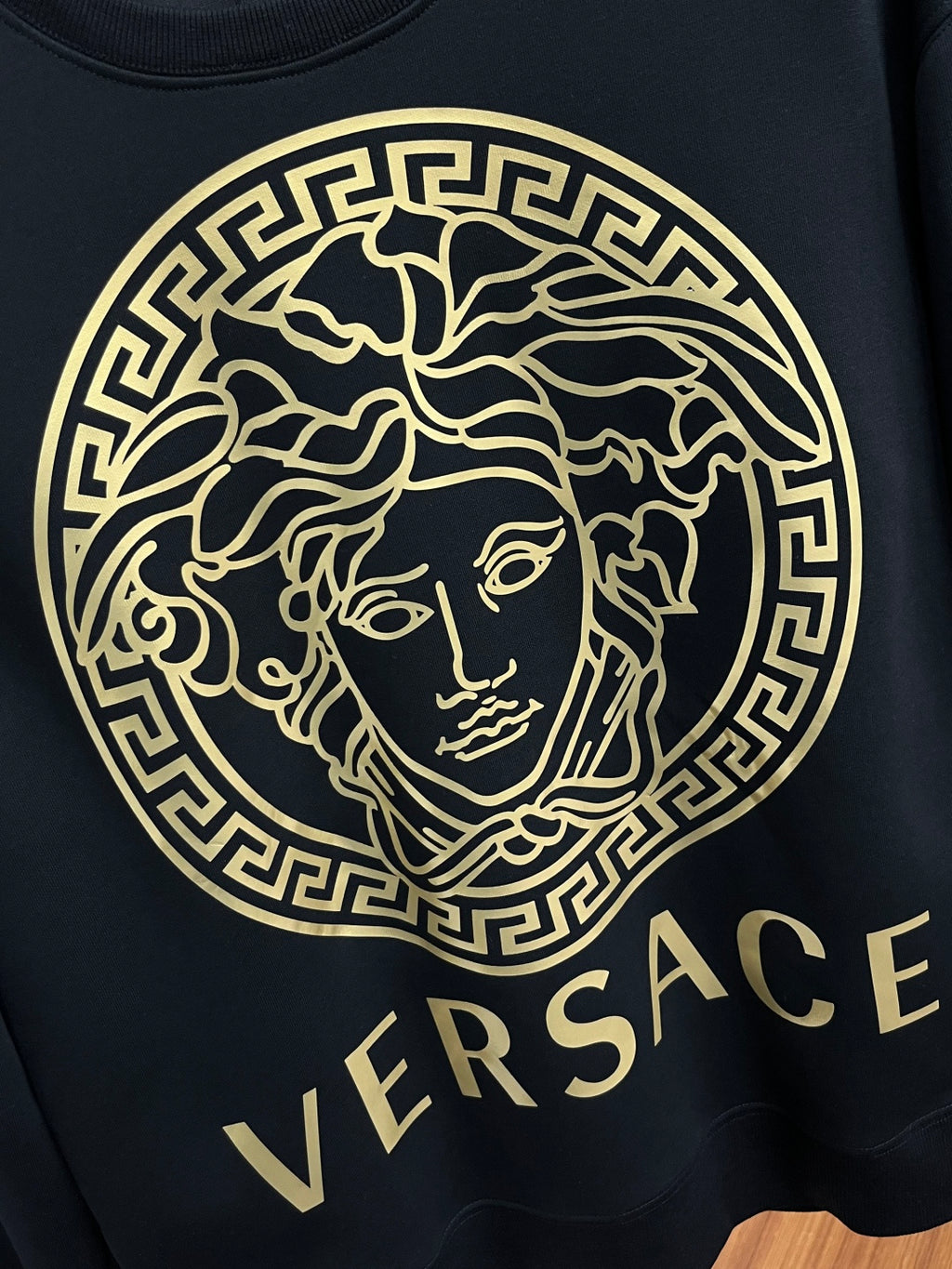 Versace crewneck sweatshirt close-up, black with large gold Medusa emblem and VERSACE text