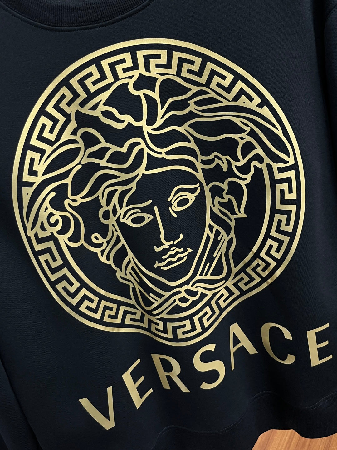 Versace crewneck sweatshirt close-up, black with large gold Medusa emblem and VERSACE text
