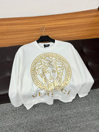 White crewneck sweatshirt hanging with gold Medusa emblem and partial VERSACE lettering