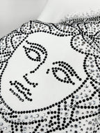 White sweatshirt with studded Medusa-style face graphic, close-up