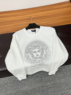 White crewneck sweatshirt with studded Medusa-style face graphic on the front