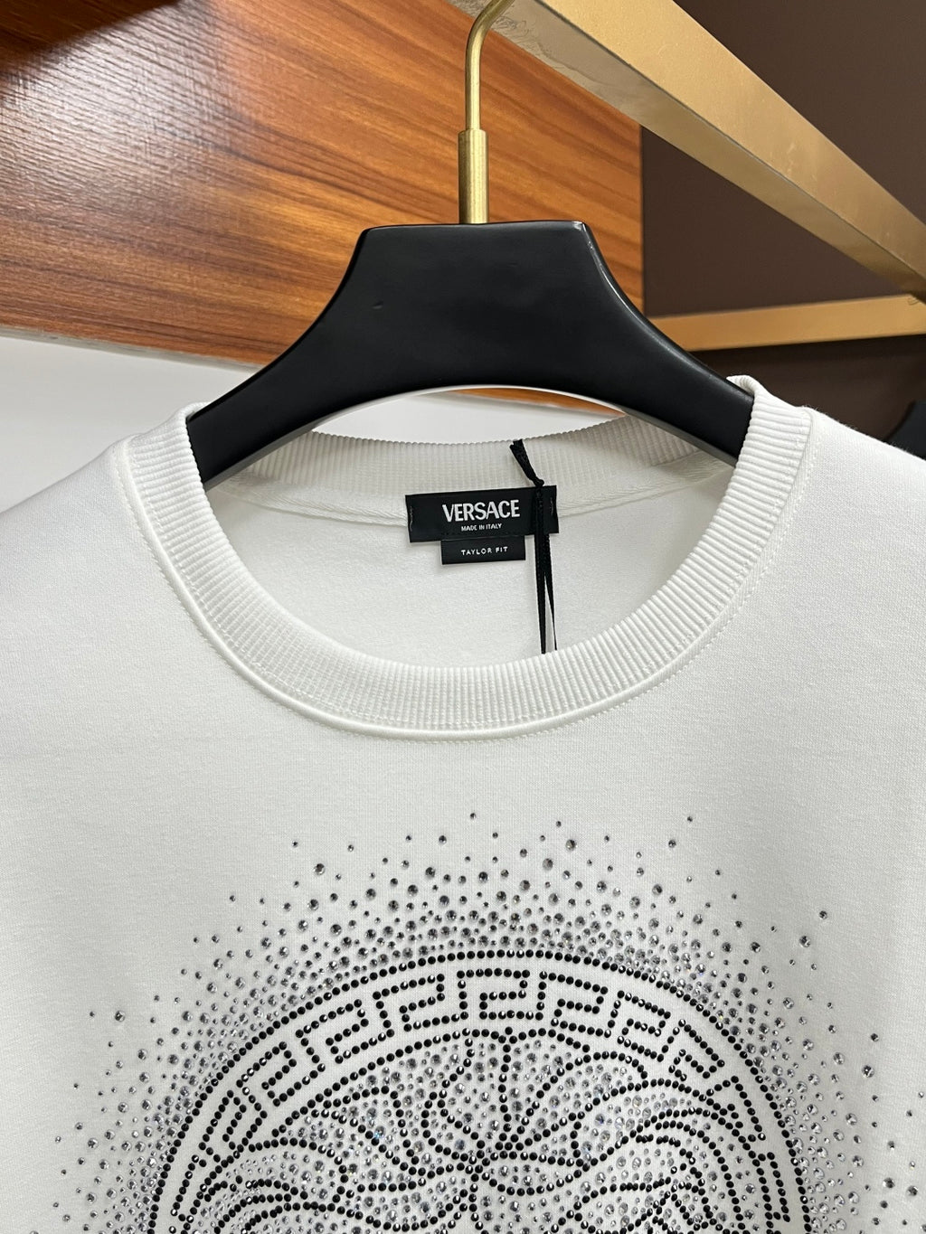 White crewneck sweatshirt with ribbed collar and studded Medusa-style chest graphic