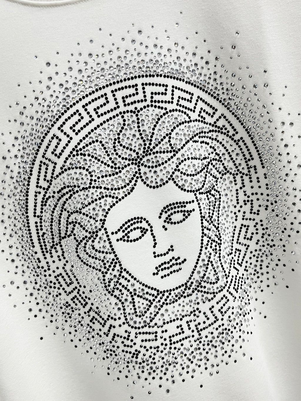 White sweatshirt featuring studded Medusa-style face print within a circular pattern