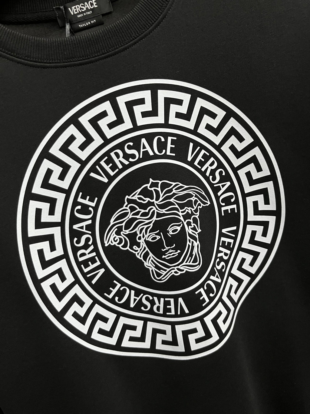 Black crewneck sweatshirt with large circular Greek-key logo and Medusa emblem