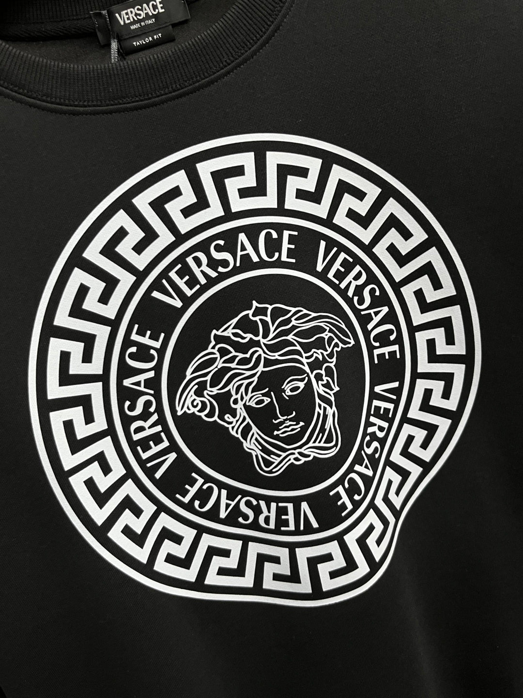 Black crewneck sweatshirt with large circular Greek-key logo and Medusa emblem