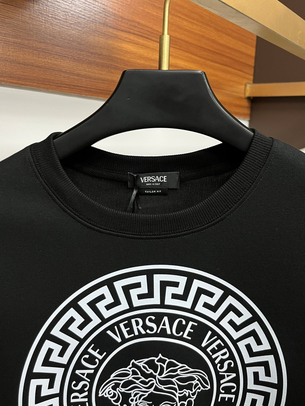 Black crewneck sweatshirt neckline with small Versace logo and ring crest print