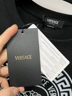 Black crewneck sweatshirt collar with attached Versace hang tag