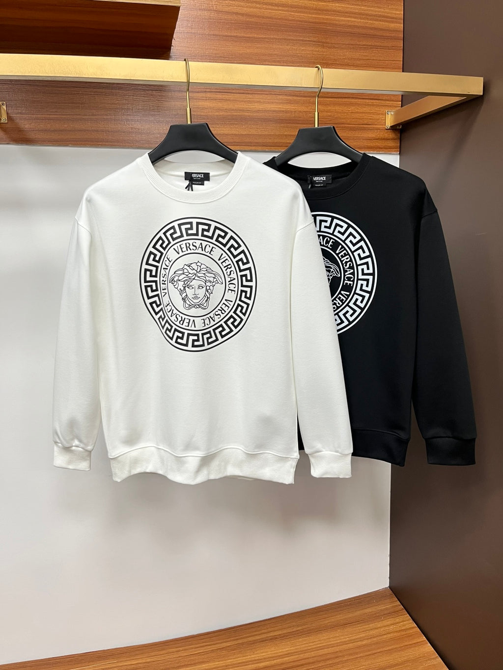 Pair of crewneck sweatshirts: white and black with circular Versace logo graphic