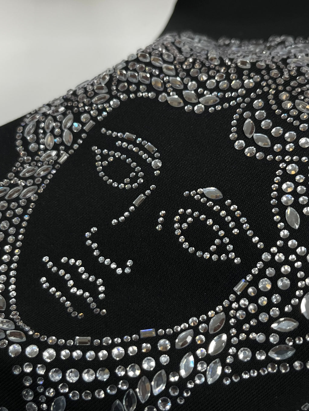 Black sweatshirt sleeve close-up with rhinestone ornamental pattern