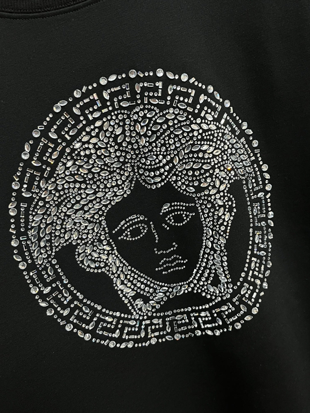 Black crewneck sweatshirt with detailed jeweled face emblem graphic