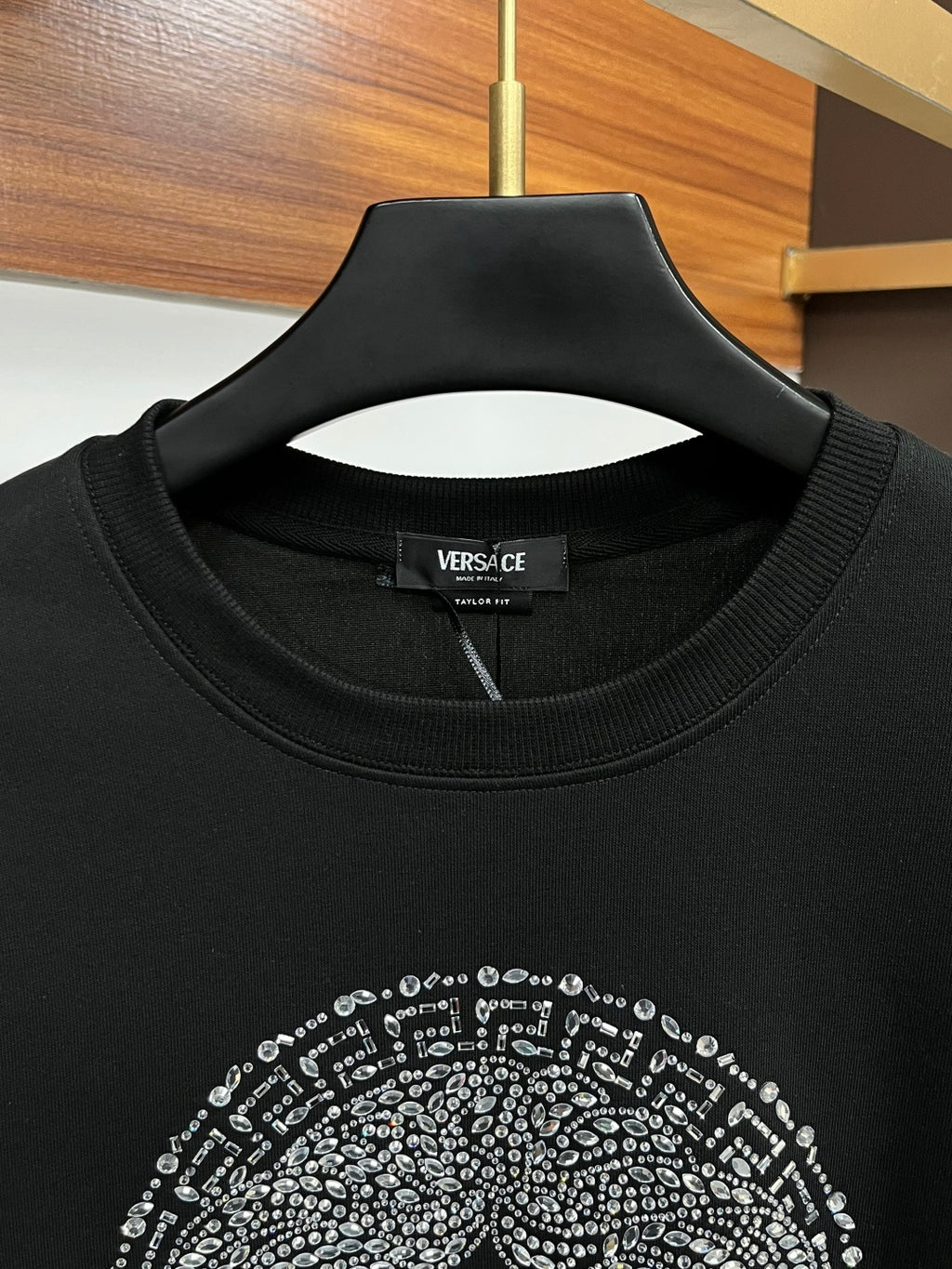 Black crewneck sweatshirt close-up of jeweled face graphic near collar