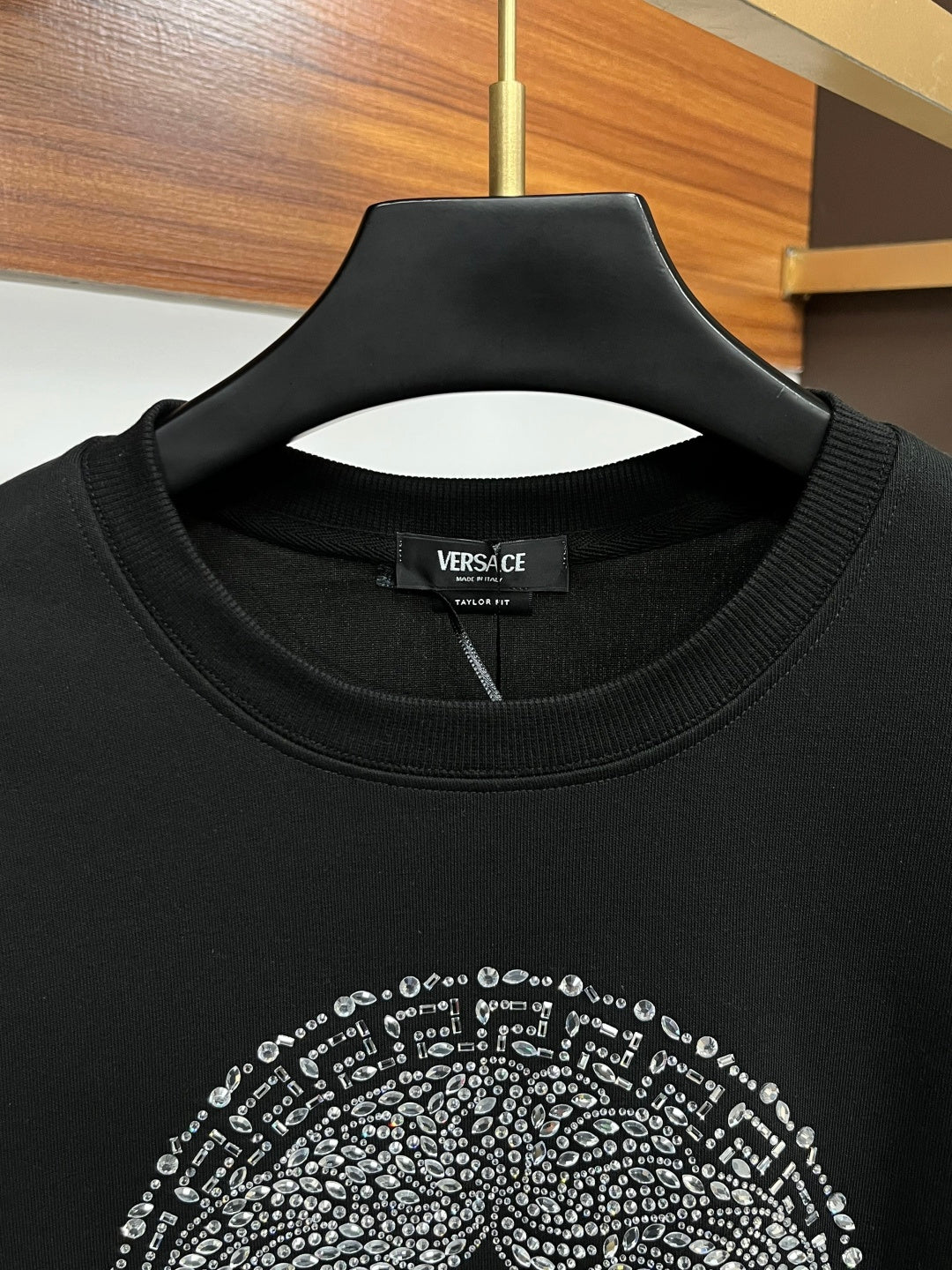 Black crewneck sweatshirt close-up of jeweled face graphic near collar
