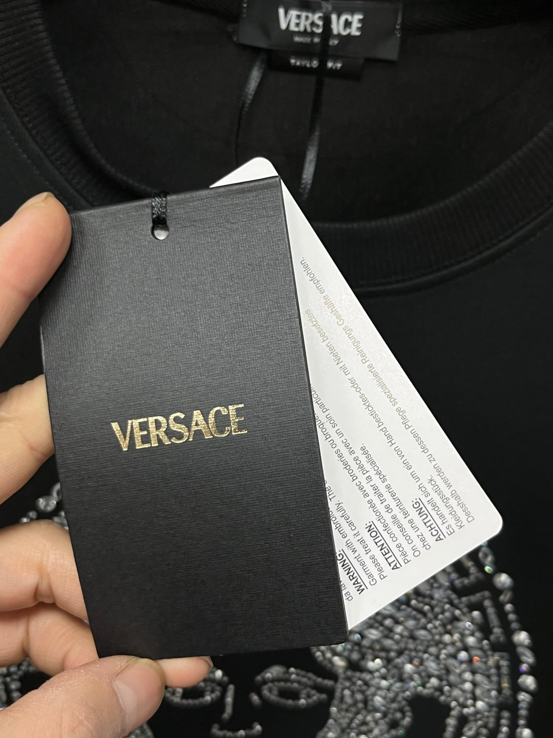 Versace black sweatshirt hangtag on neckline, fabric label visible