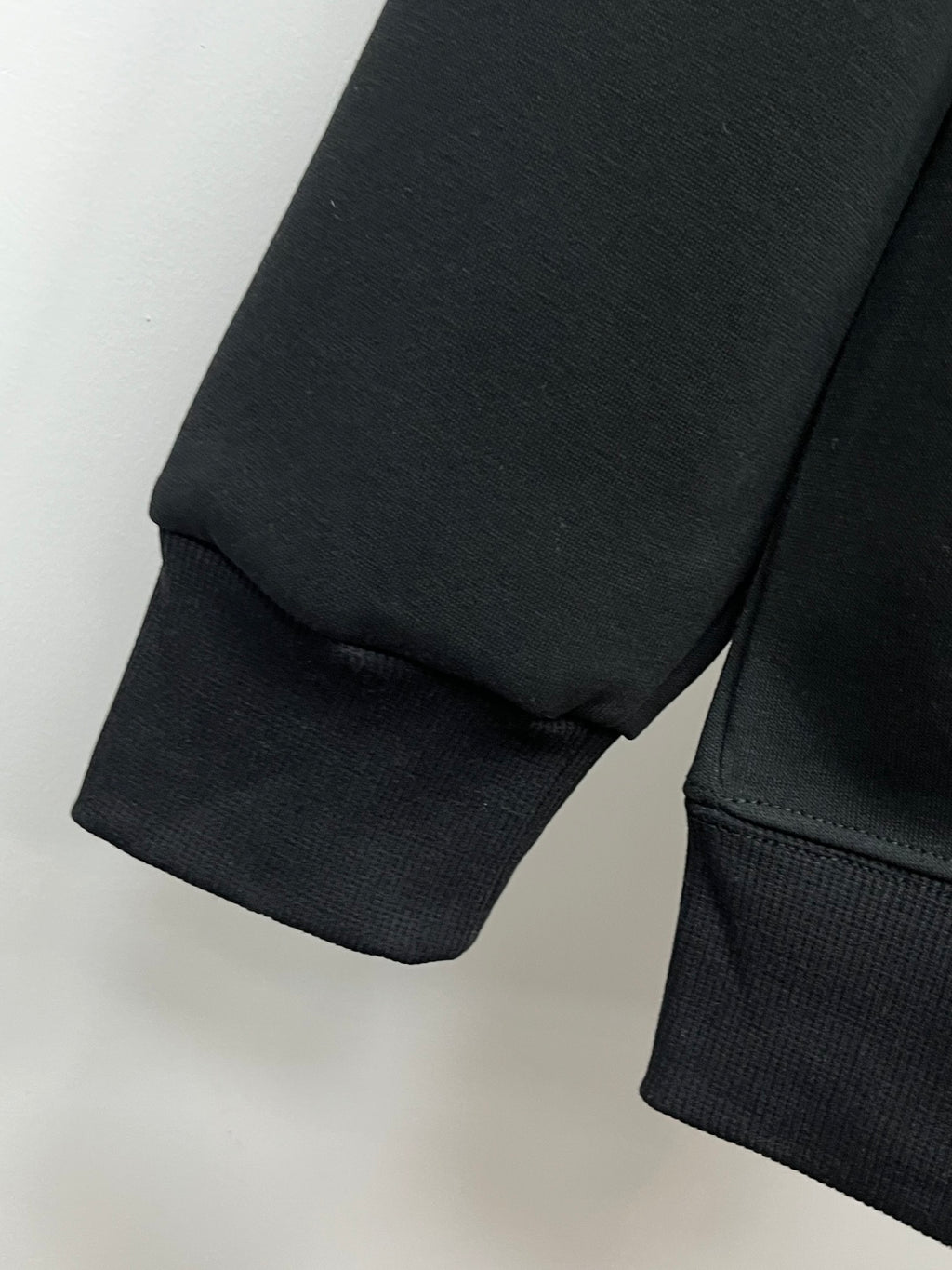 Black crewneck sweatshirt sleeve cuff and hem detail